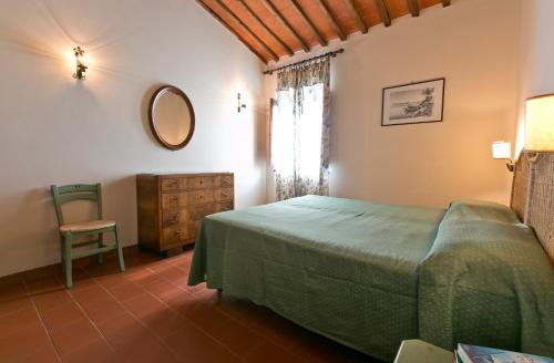 a bedroom with a bed and a chair and a mirror at Agriturismo il Torrione in Poggibonsi