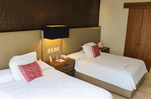 two beds in a hotel room with white sheets and red pillows at Hotel Lindo Ajijic Bed & Breakfast in Ajijic