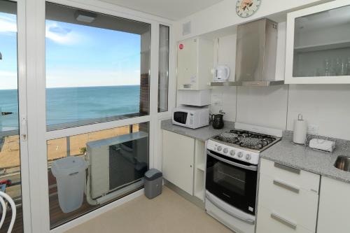 a white kitchen with a view of the ocean at DeptosVip - Gascón in Mar del Plata