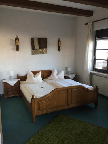 Un dormitorio con una gran cama de madera con almohadas blancas. en Landhaus Waldziegelhütte, en Waldmohr