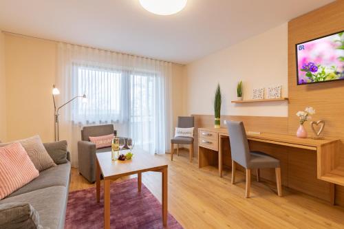 a living room with a couch and a desk with chairs at Aparthotel Grabner in Bad Füssing