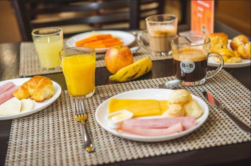 a table with plates of food and glasses of orange juice at B&B Hotels Rio Copacabana Posto 5 in Rio de Janeiro