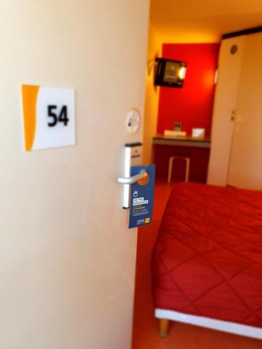 a room with a bed and a sign on the wall at Premiere Classe Nancy Est Essey in Essey-lès-Nancy