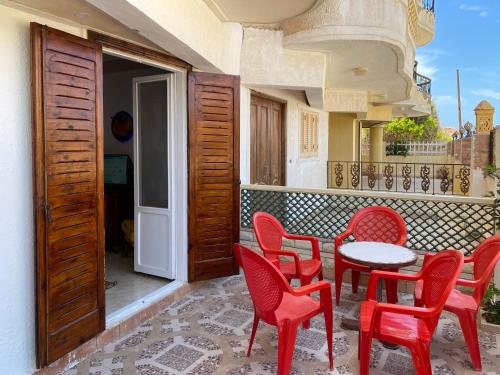 un patio con sedie rosse e un tavolo sul balcone. di Seaside Two-Bedroom Chalet Sidi Krir a Sidi Krir