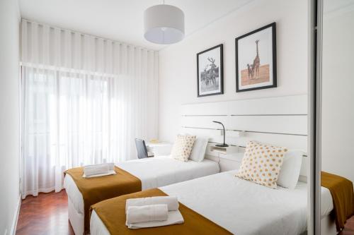 リスボンにあるCentral Family and Executive Apartmentのベッド2台と窓が備わるホテルルームです。