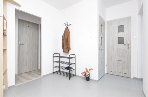 a white hallway with a black shelf and a door at Rooms4Less in Gdańsk