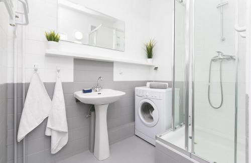 a white bathroom with a washing machine and a sink at Rooms4Less in Gdańsk