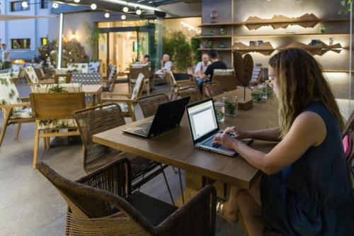 a woman sitting at a table using a laptop at Palmyra Beach Hotel in Athens