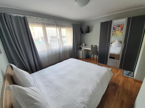 a bedroom with a white bed and a window at Le Merle Châtelain in Sion