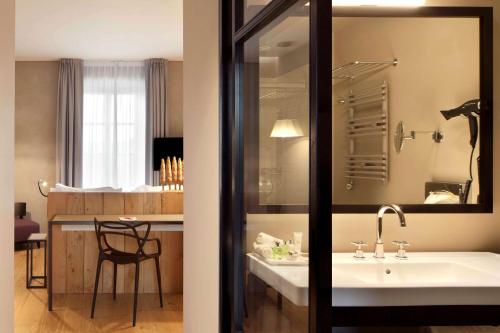 a bathroom with a sink and a kitchen with a table at NH Collection Torino Piazza Carlina in Turin