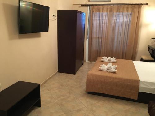 a bedroom with a bed and a tv and a ottoman at Studio Konstantinos in Parga