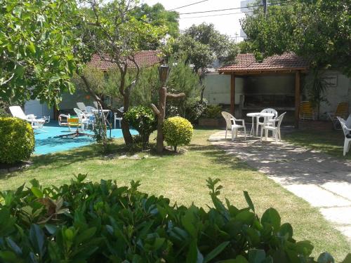 einen Garten mit Stühlen, einem Tisch und einem Pool in der Unterkunft Hotel La Argentina in San Clemente del Tuyú