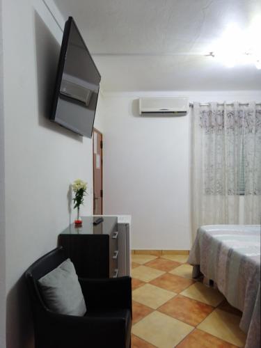a living room with a chair and a television at Hostel Boutique Marisol in Monte Gordo