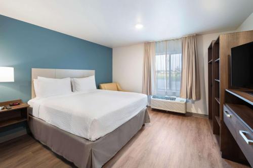 a bedroom with a large bed and a window at WoodSpring Suites Dallas Plano Central Legacy Drive in Plano
