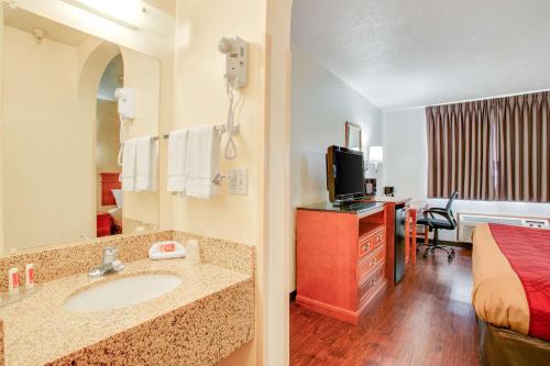 a hotel room with a bathroom with a sink and a bed at Econo Lodge Inn & Suites Albuquerque East I-40 Eubank Exit in Albuquerque