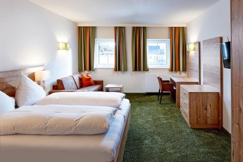 a hotel room with two beds and a desk at Hotel Flatscher in Stuhlfelden