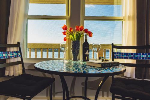 una mesa con un jarrón de flores y una botella de vino en Bearskin Neck Motor Lodge, en Rockport
