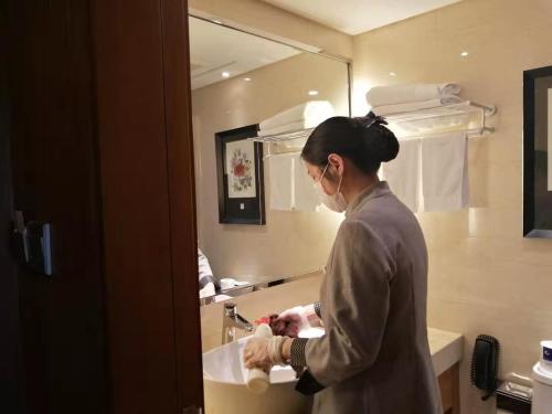 una mujer lavándose las manos en el lavabo del baño en Ramada Nanjing, en Jiangning