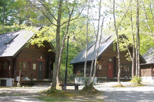 a wooden cabin with red doors in the woods at Hakuba Brownie Cottages in Hakuba
