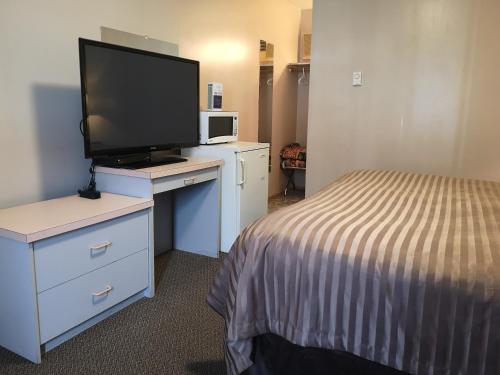 a hotel room with a bed and a flat screen tv at Ranchland Villa Motel in Merritt