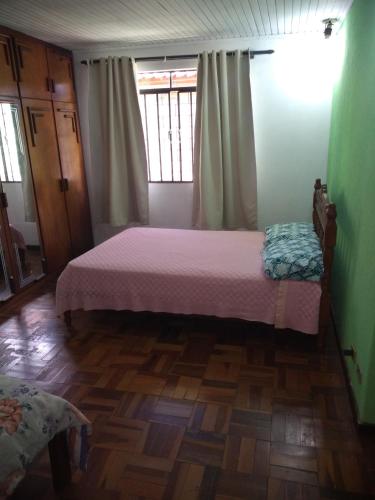 um quarto com uma cama e piso em madeira em Pousada Santa Felicidade, garagem T em Curitiba