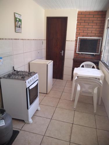 a kitchen with a stove and a table and a chair at Pousada Santa Felicidade, garagem T in Curitiba