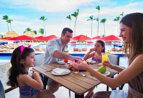 a family eating food at a table at a resort at Royalton Bavaro, An Autograph Collection All-Inclusive Resort & Casino in Punta Cana