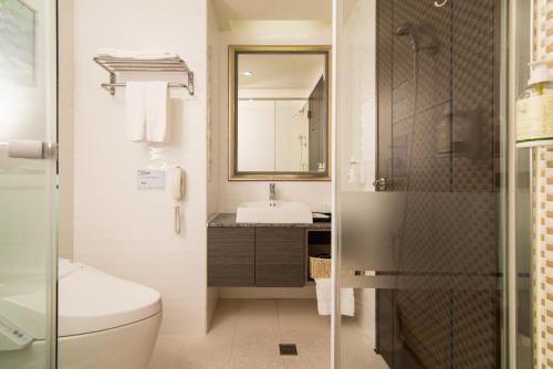 a bathroom with a toilet and a sink and a mirror at Arsma Hotel in Hualien City