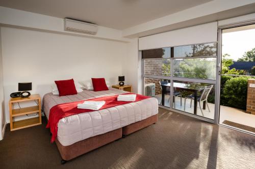 una camera da letto con balcone e letto con cuscini rossi. di Charlestown Terrace Apartments a Newcastle