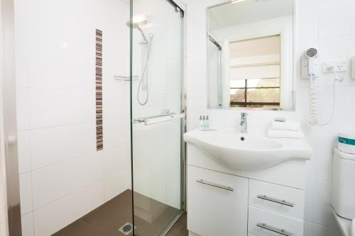 a bathroom with a shower, sink, and mirror at Charlestown Terrace Apartments in Newcastle