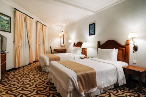 a hotel room with two beds and two tables at Hotel De' La Ferns, Cameron Highlands in Cameron Highlands