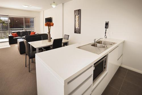 a kitchen with a sink and a living room at Charlestown Terrace Apartments in Newcastle