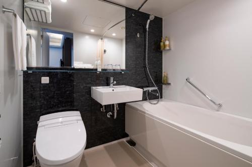 a bathroom with a toilet and a sink and a bath tub at Shin Yokohama Grace Hotel in Yokohama