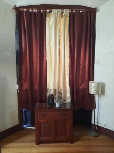 a room with red curtains and a table with a lamp at Escolta's Homey Lodge in Vigan