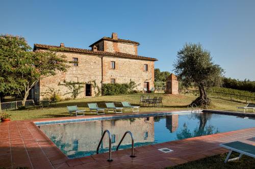 a house with a swimming pool in front of a building at Castello di Bossi in Castelnuovo Berardenga