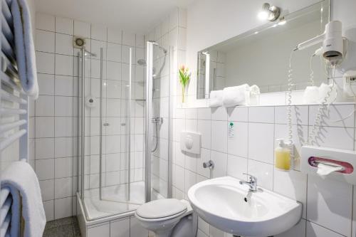 a white bathroom with a sink and a shower at art Hotel Körschen in Essen