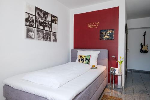 a bedroom with a white bed with a red wall at art Hotel Körschen in Essen
