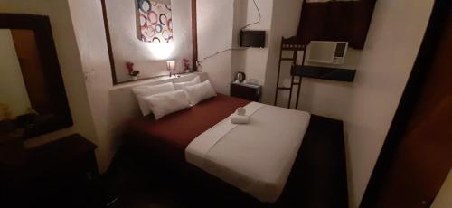 a small room with a bed with a white bedspread at Escolta's Homey Lodge in Vigan