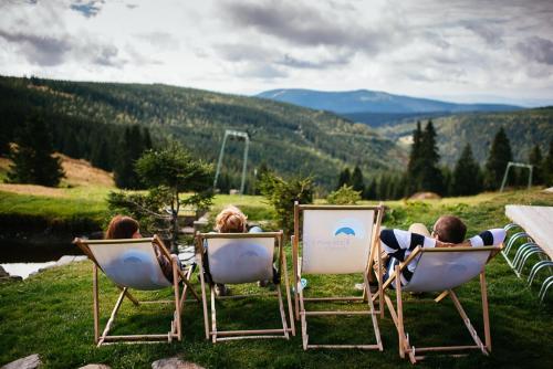a group of people sitting in chairs in the grass at Penzion Andula Friesovy boudy in Strážné