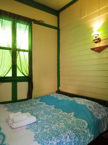 a bed in a room with a window and towels at Baan Tepa Boutique House in Bangkok