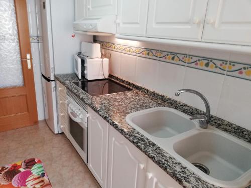 a kitchen with a sink and a microwave at Parquemar III-IV Solo Familias!!! Serviplaya in Playa de Xeraco