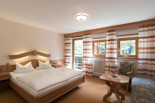 a bedroom with a bed and a table and windows at Hotel Gasthof Hereth in Wirsberg