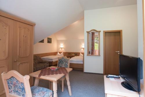 ein Wohnzimmer mit einem TV, einem Tisch und Stühlen in der Unterkunft Hotel Gasthof Hereth in Wirsberg