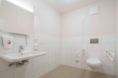 ein weißes Bad mit einem Waschbecken und einem WC in der Unterkunft AS Ferienzentrum in Butjadingen
