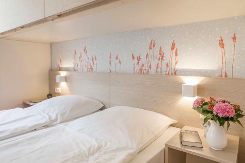 a bedroom with a white bed and a vase with flowers at AS Ferienzentrum in Butjadingen