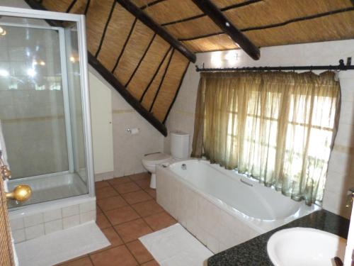 a bathroom with a tub and a toilet and a sink at Foundry Guest Lodge in Pretoria