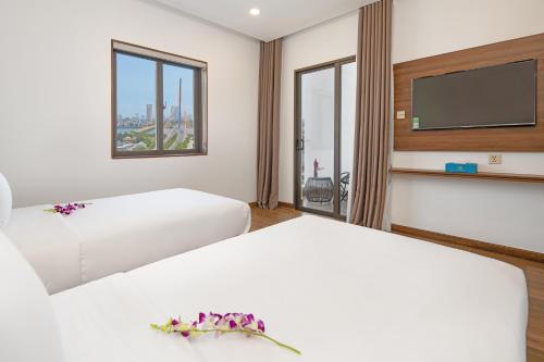 a hotel room with two beds and a flat screen tv at Gold Plaza Hotel Da Nang in Da Nang