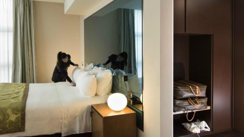 a woman is putting pillows on a bed in a hotel room at Best Western Premier BHR Treviso Hotel in Quinto di Treviso