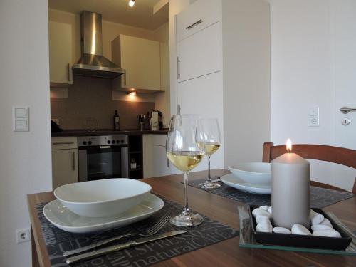 uma cozinha com uma mesa com pratos brancos e copos de vinho em Appartement - Haus Winterberg em Winterberg