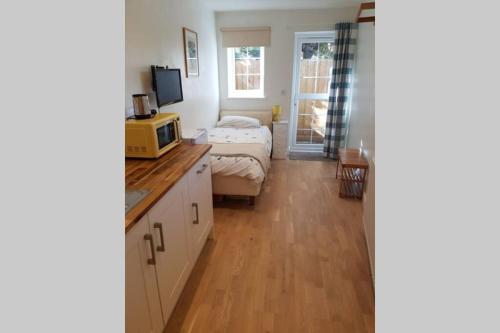 a small room with a bed and a microwave at Cosy, self contained annex in Cambridge